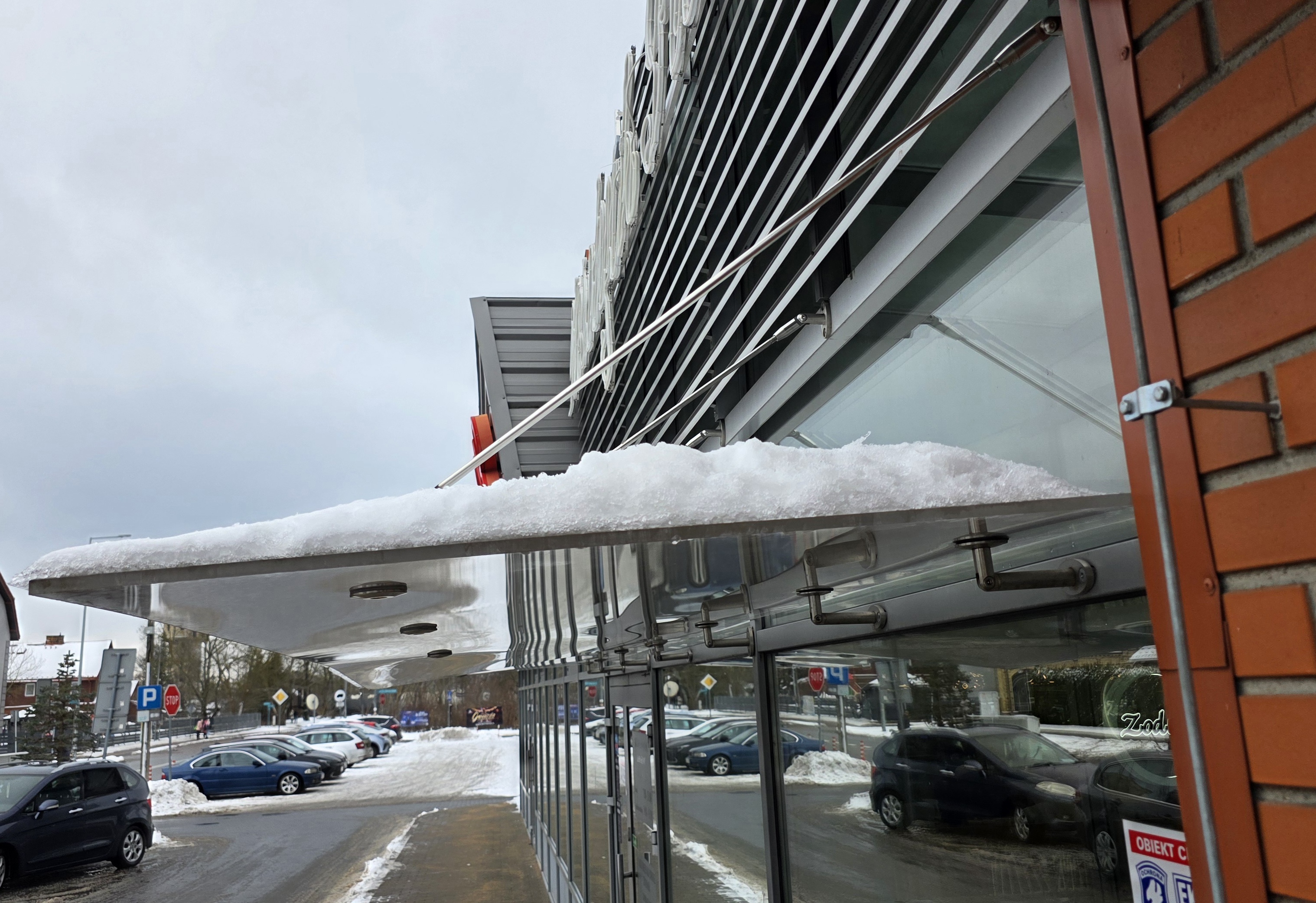 Zadaszenie z poliwęglanu z zalegającym śniegiem – widok z boku nowoczesnego daszka nad wejściem w Białymstoku